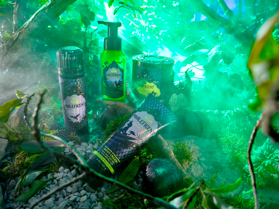 Products from Bath & Body Works Disney Villains collection on rocks, surrounded by tree branches