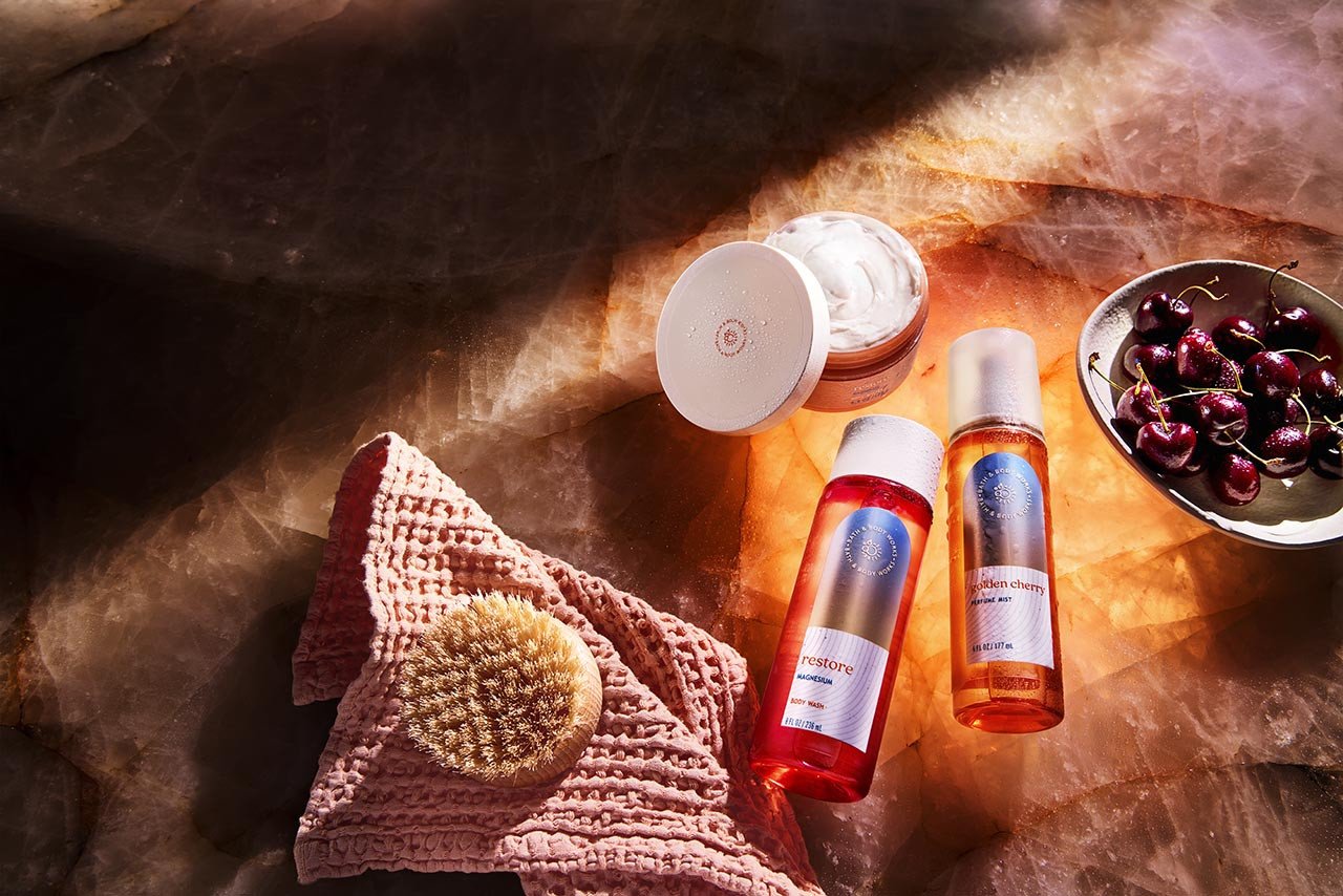 Bath & Body Works wellness products on a stone background with cherries and a towel