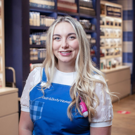 Bath & Body Works employee in a store smiling at the camera.