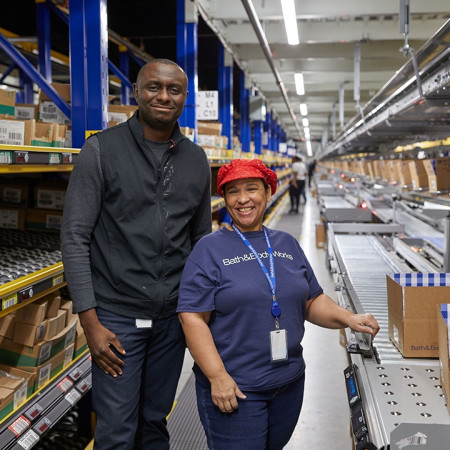 Two Bath & Body Works employees standing in a distribution center smiling.