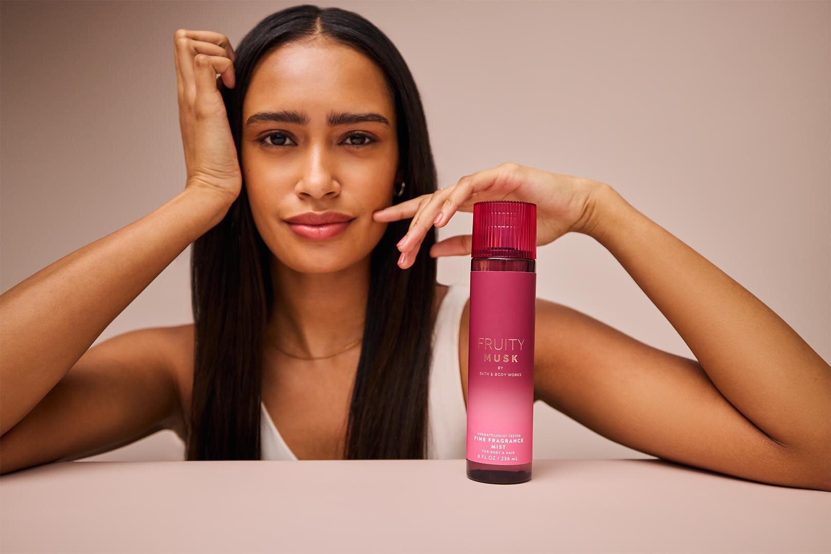 Person with hand on head behind Bath & Body Works' Fruity Musk fine fragrance mist